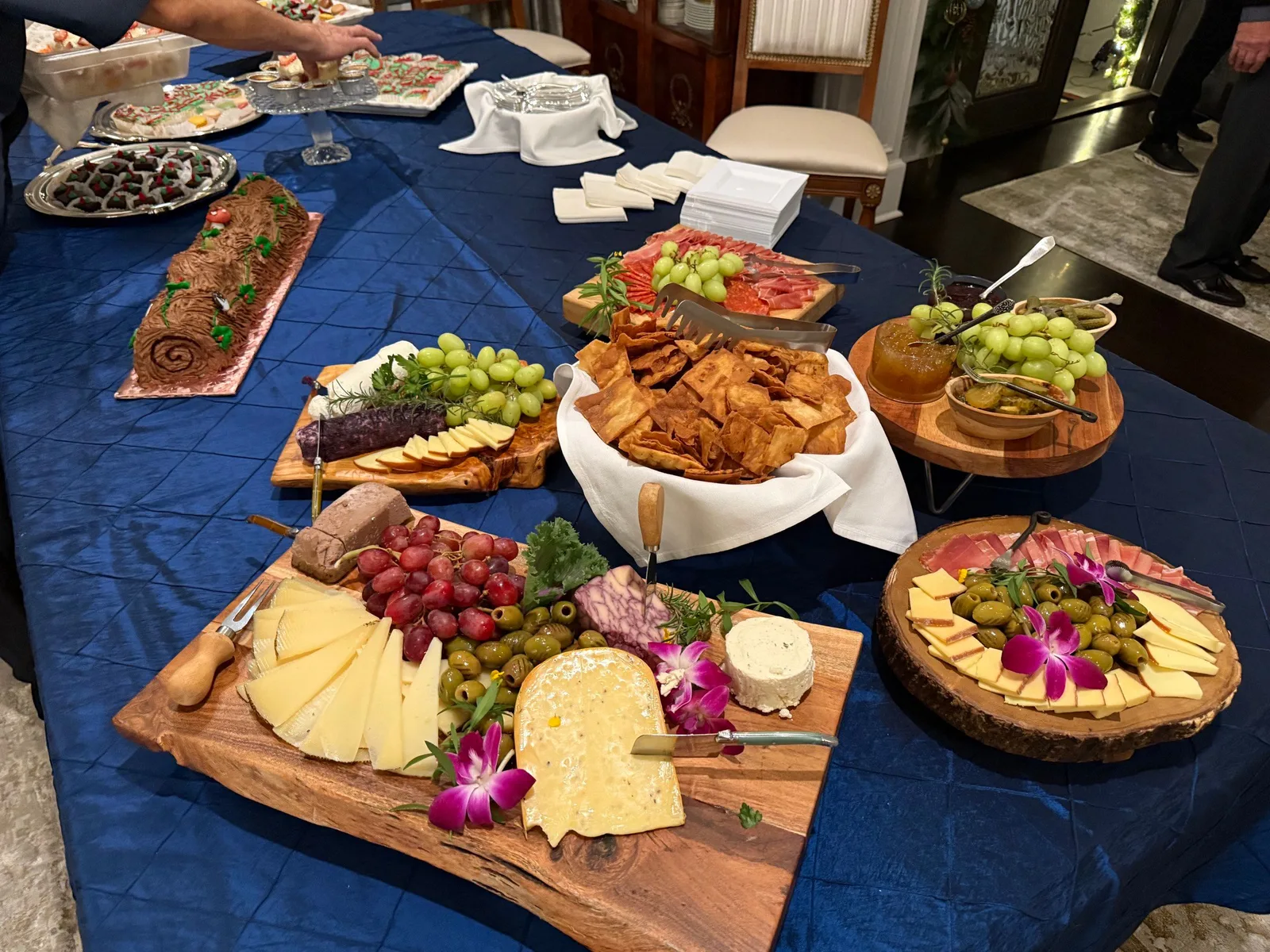 Cheese and charcuterie spread on a navy tablecloth with wooden boards and orchids