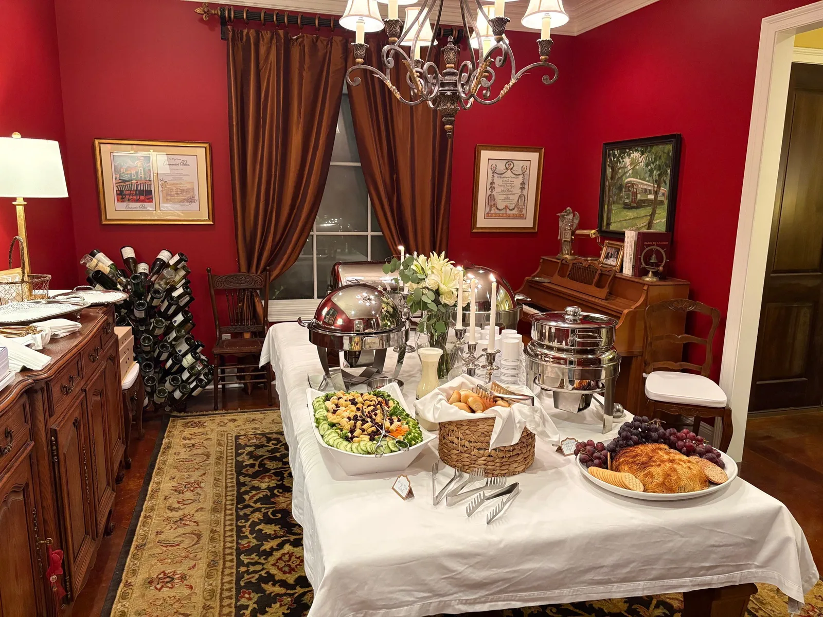 Elegant dining room buffet with salad, croissants, and chafing dishes in a red-walled room