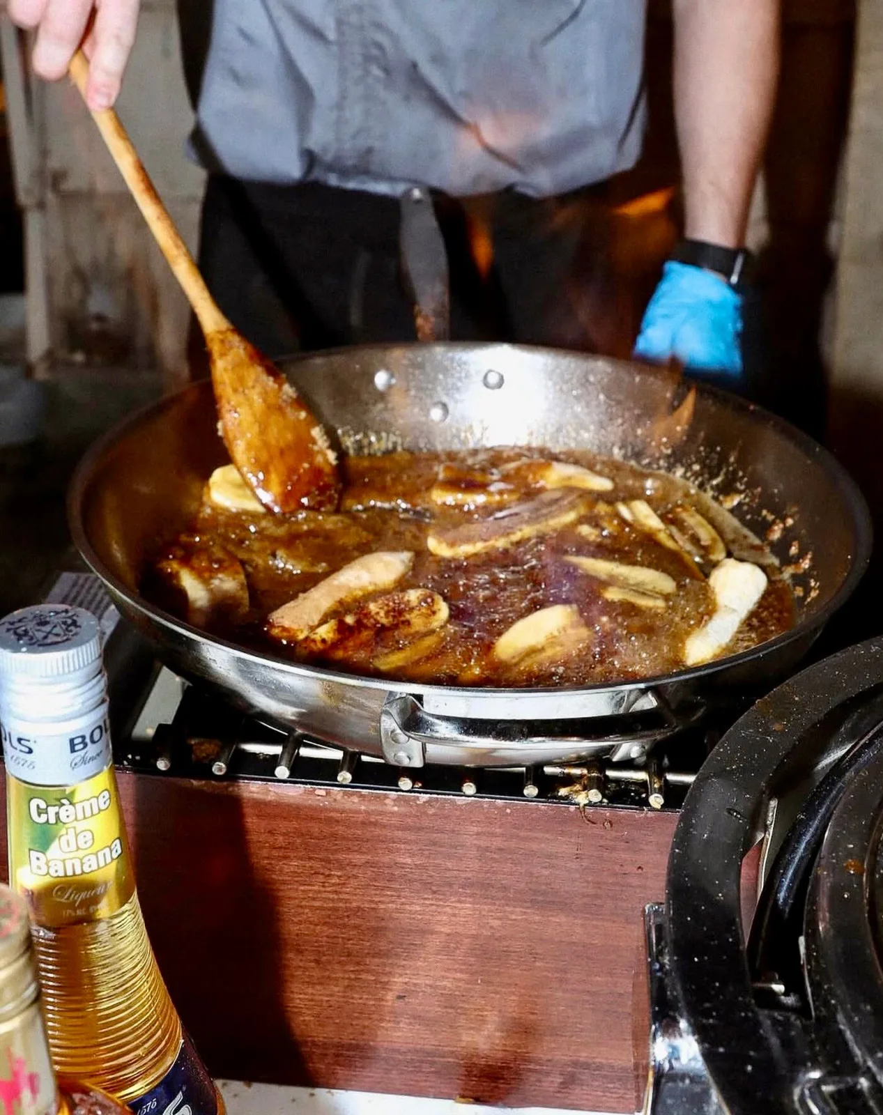 Team member preparing Bananas Foster tableside in a flambé pan