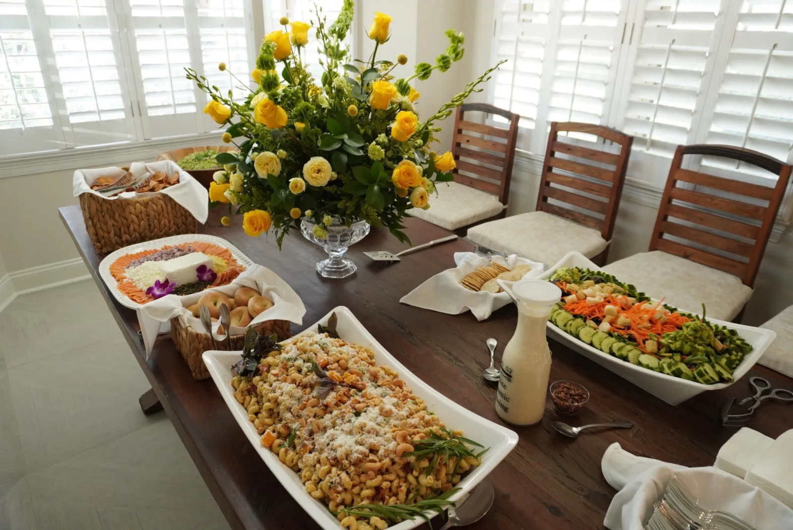 Elegant daytime table spread with pasta salad, veggie platter, and yellow flowers