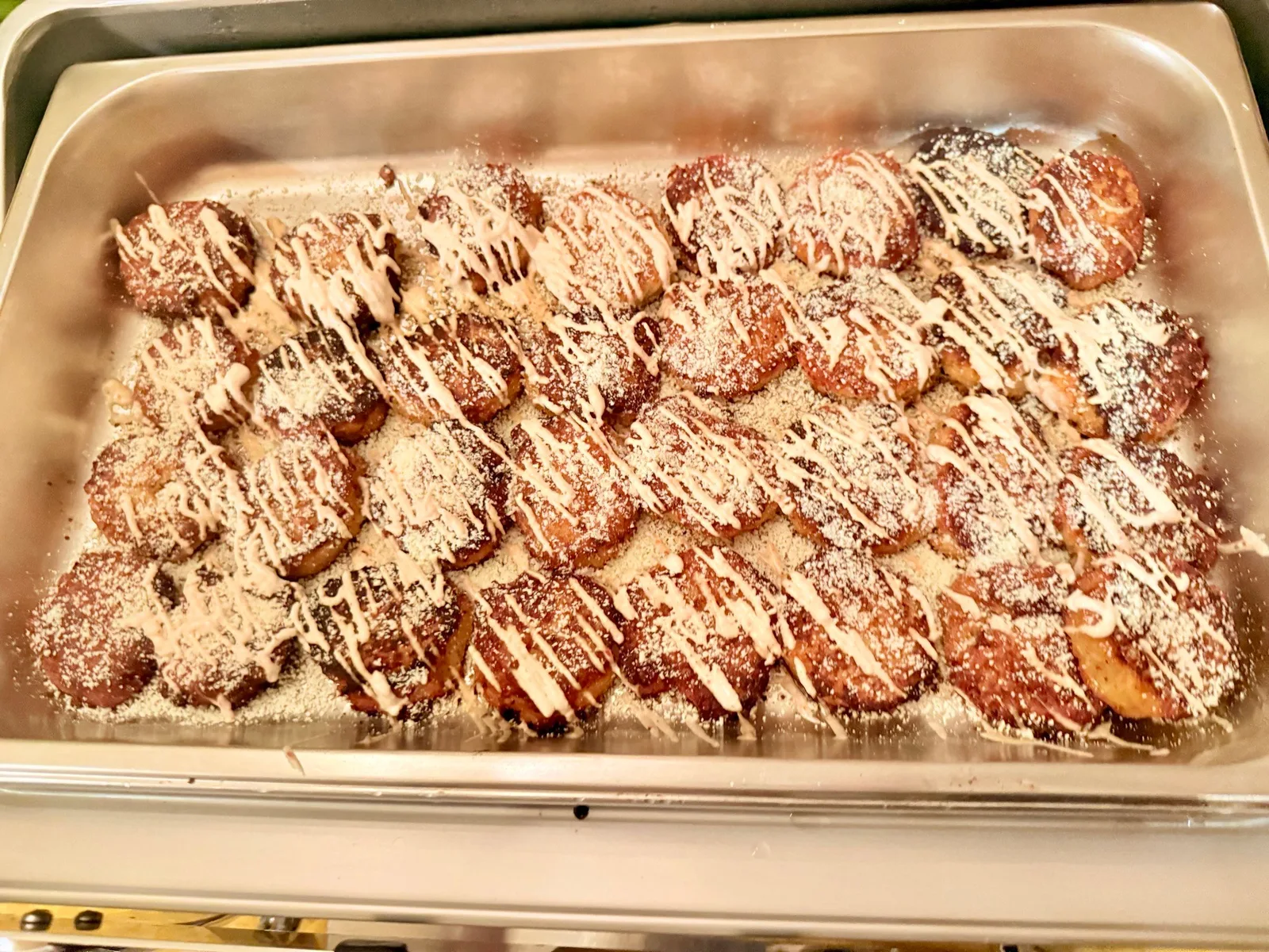 Bread pudding with white chocolate drizzle in a warming tray