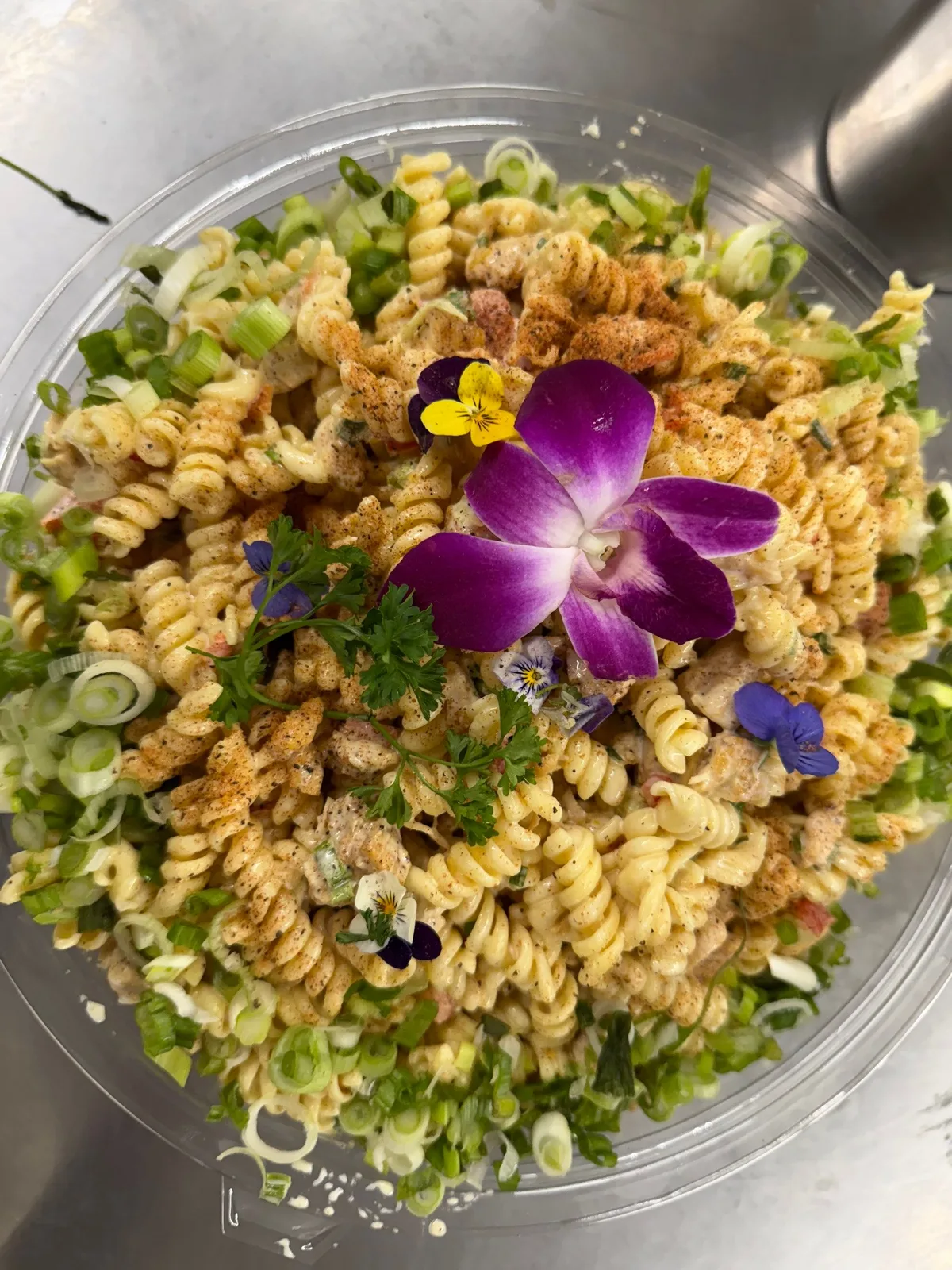 Rotini pasta salad garnished with orchids and edible flowers