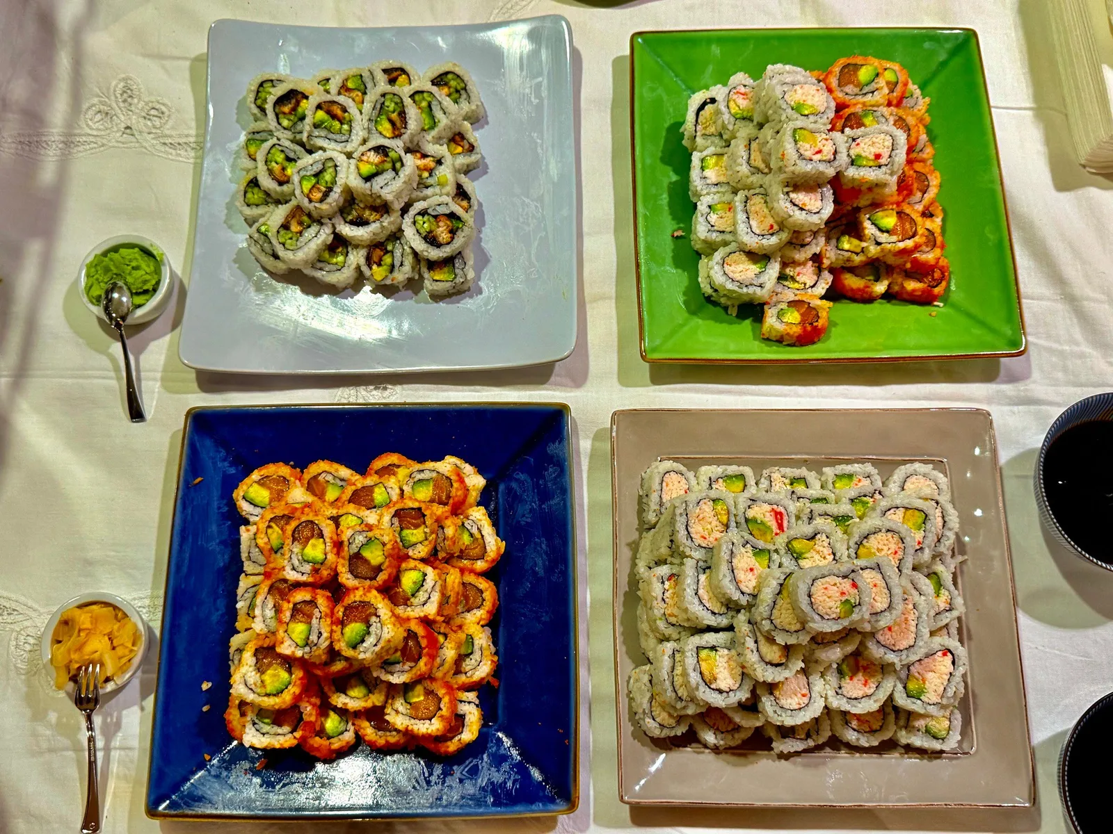 Overhead sushi rolls on four colorful plates